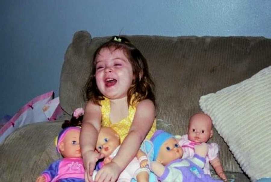 An adopted girl sits laughing with her dolls