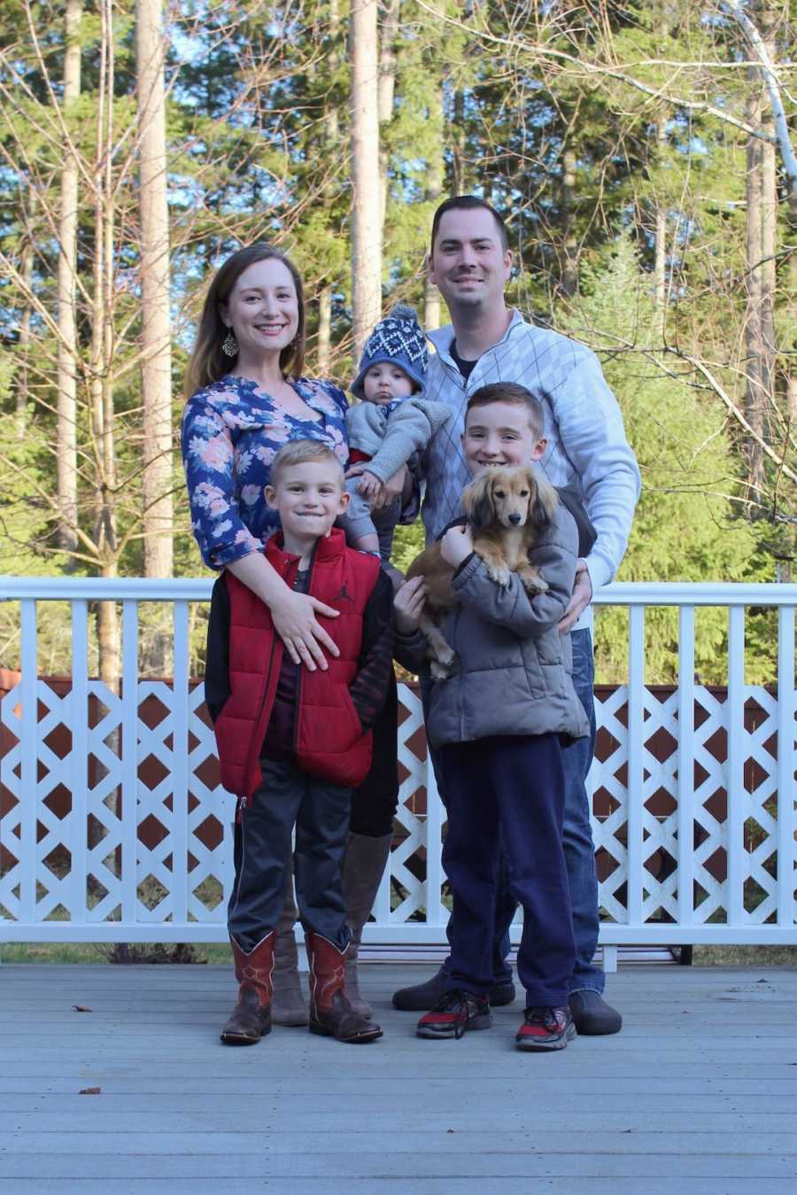 Family of five standing on balcony holding dog