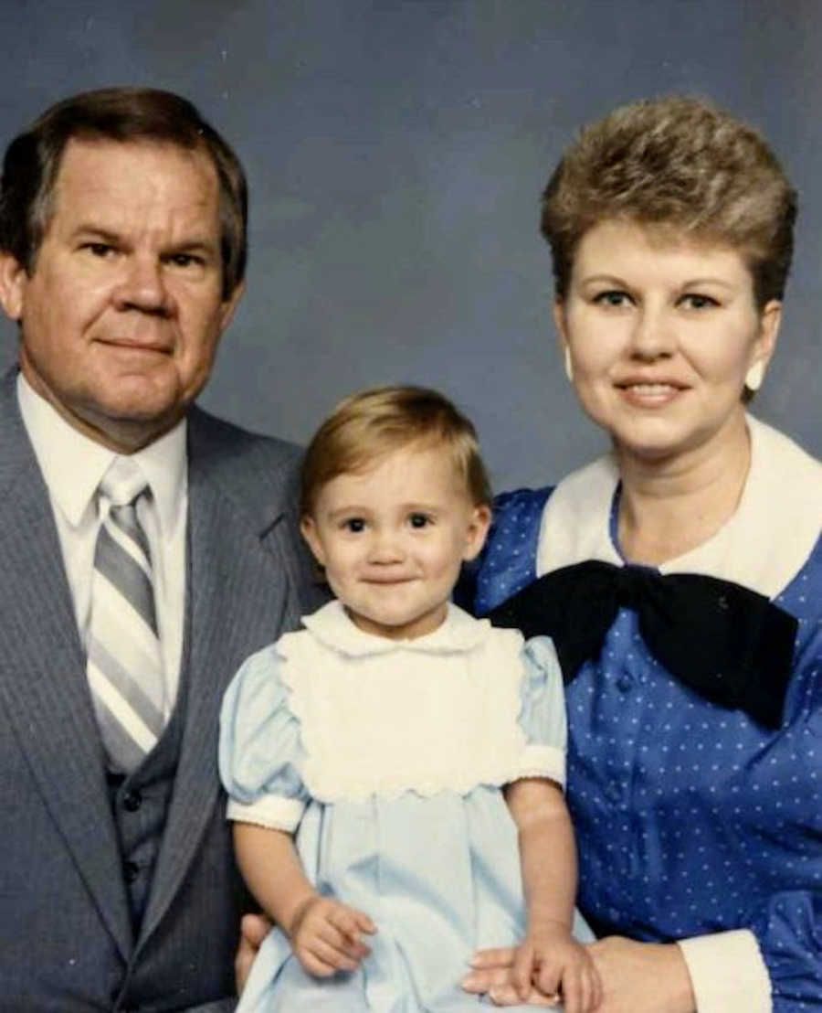 Family of three holding daughter wearing blue
