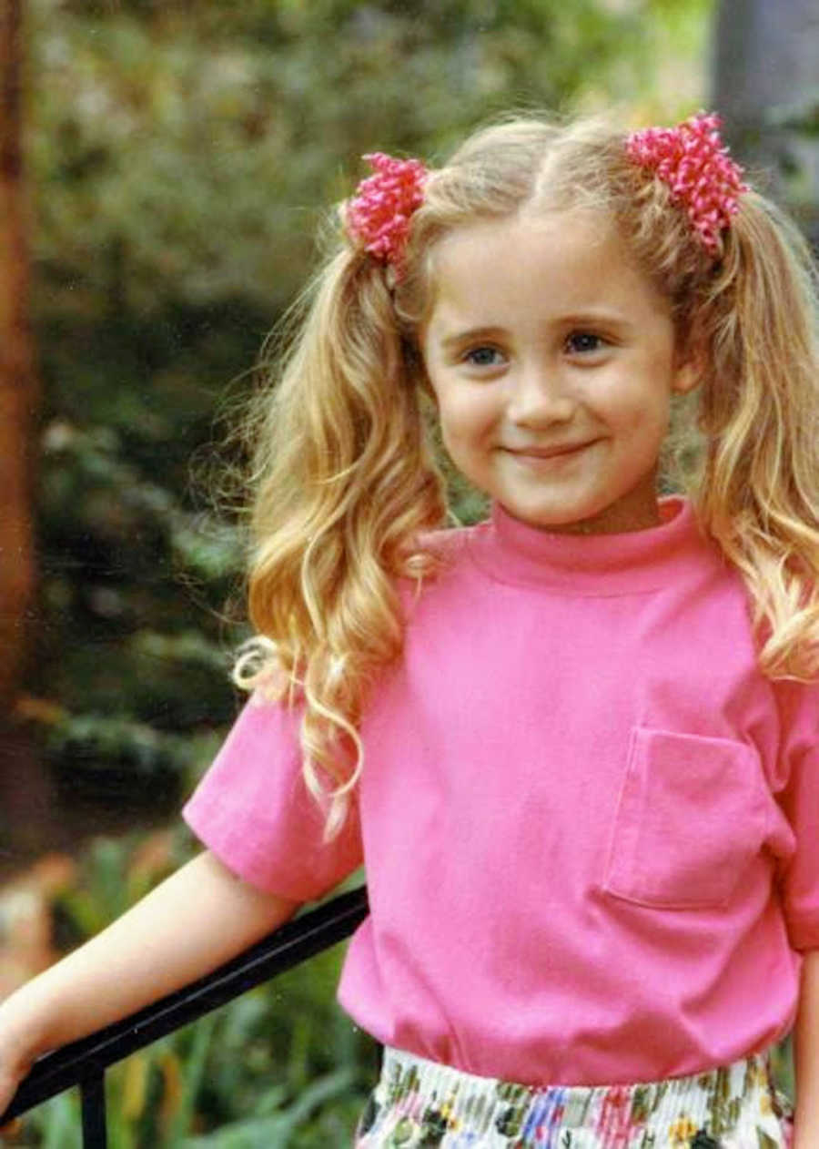 Young blonde girl with pigtails wearing pink shirt smiling outside