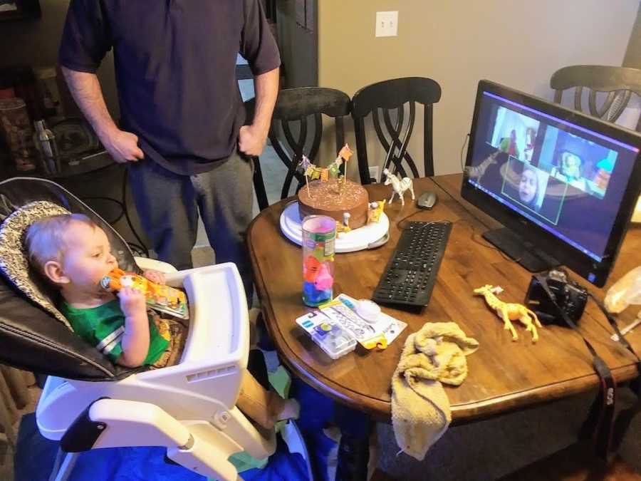 Baby boy sitting in high chair at first birthday video calling family