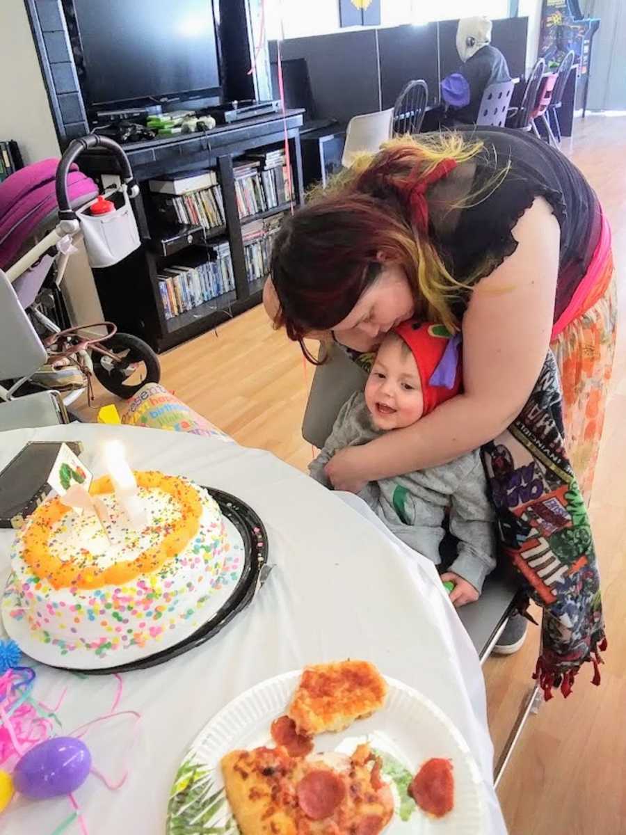 Birth mother holding son at first birthday party with cake