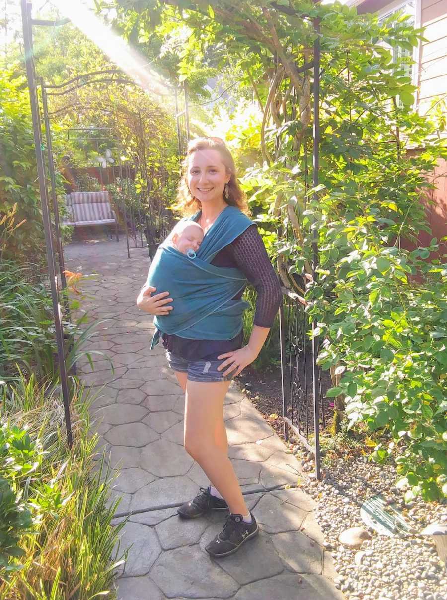 Mother standing outside wearing newborn son