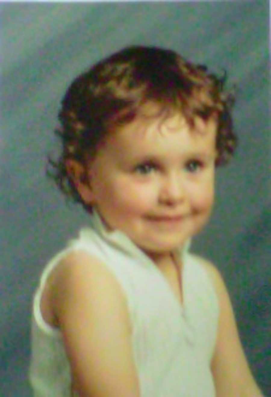 Young child with curly hair sitting for a photo