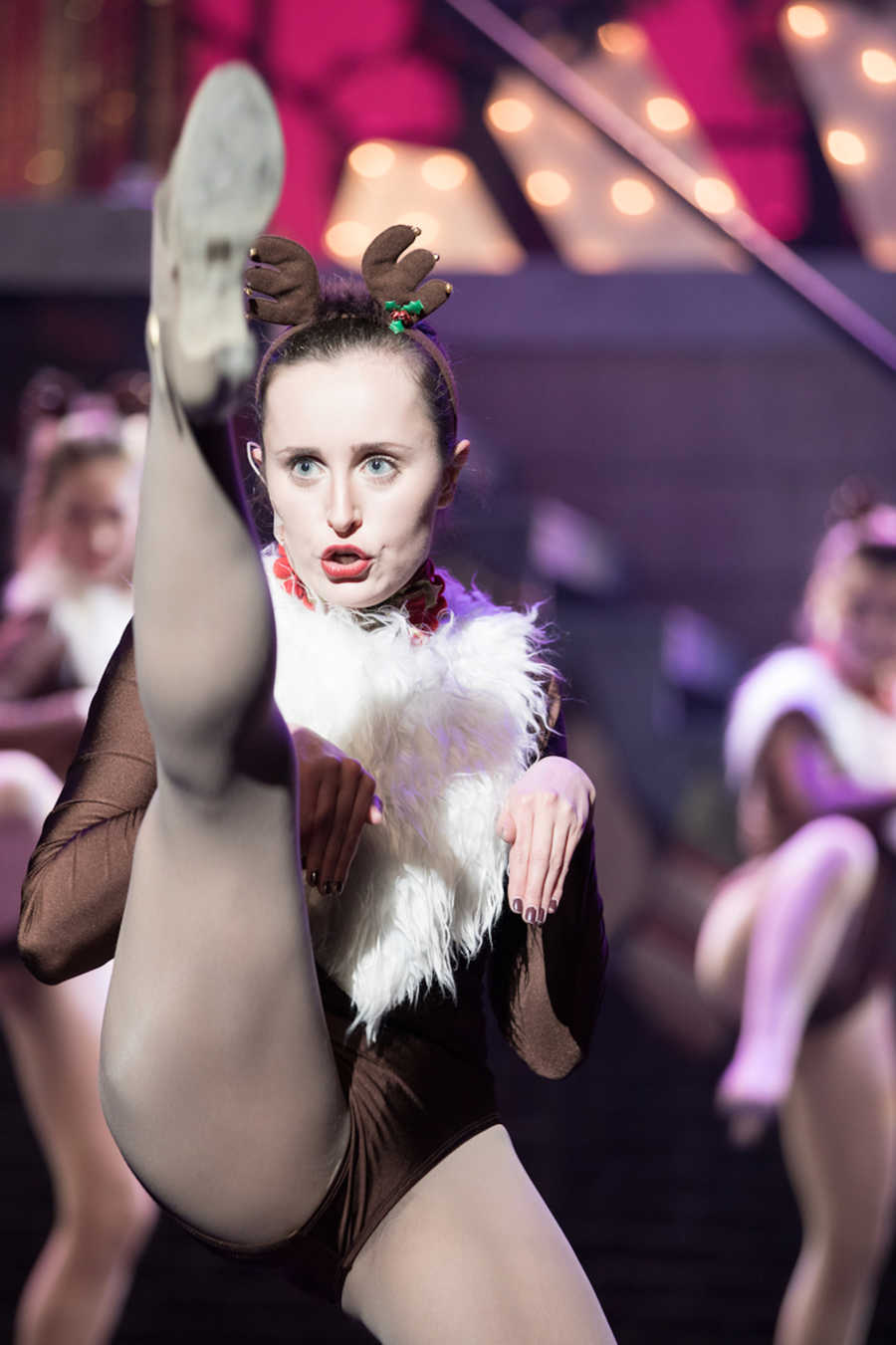 Dancer wearing reindeer antlers kicking leg up in air