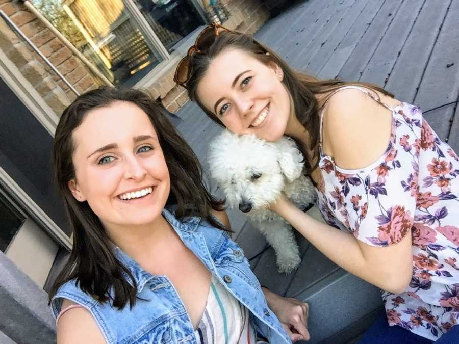 Two women sitting on steps with white small dog