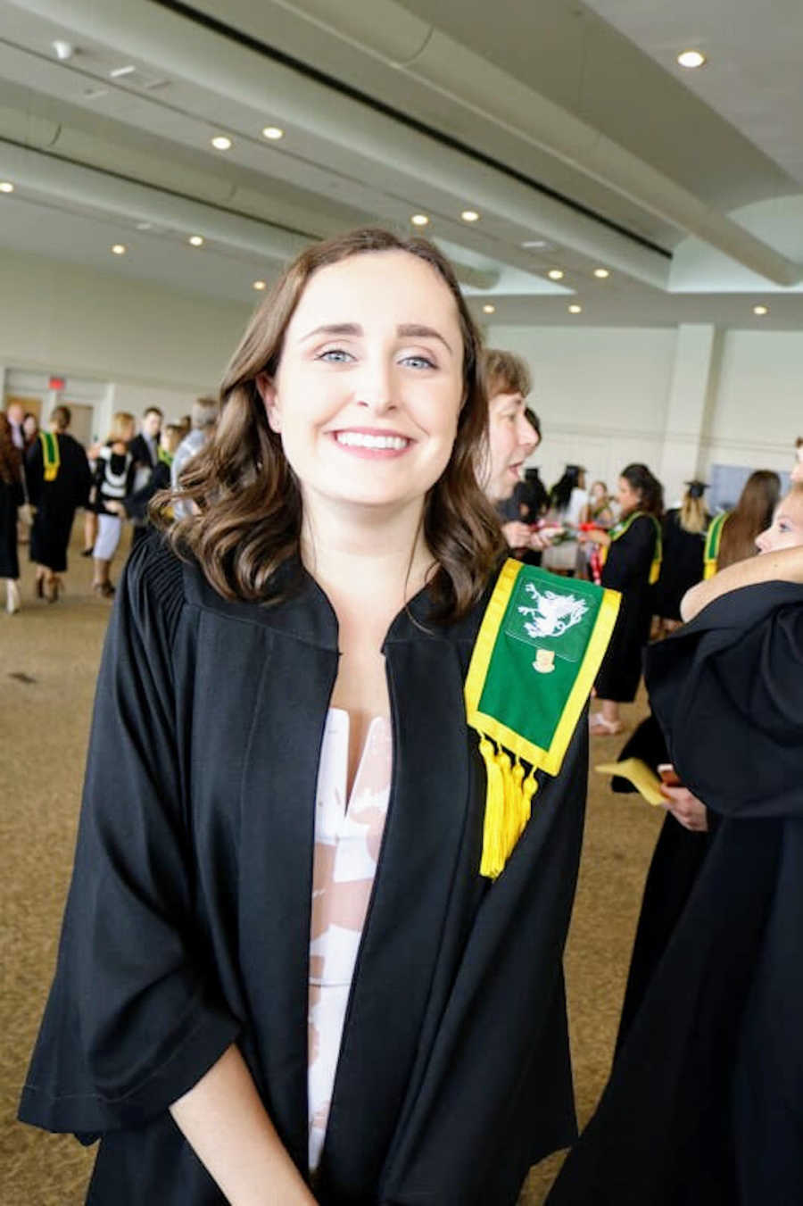 Young woman wearing graduation regalia smiling at camera