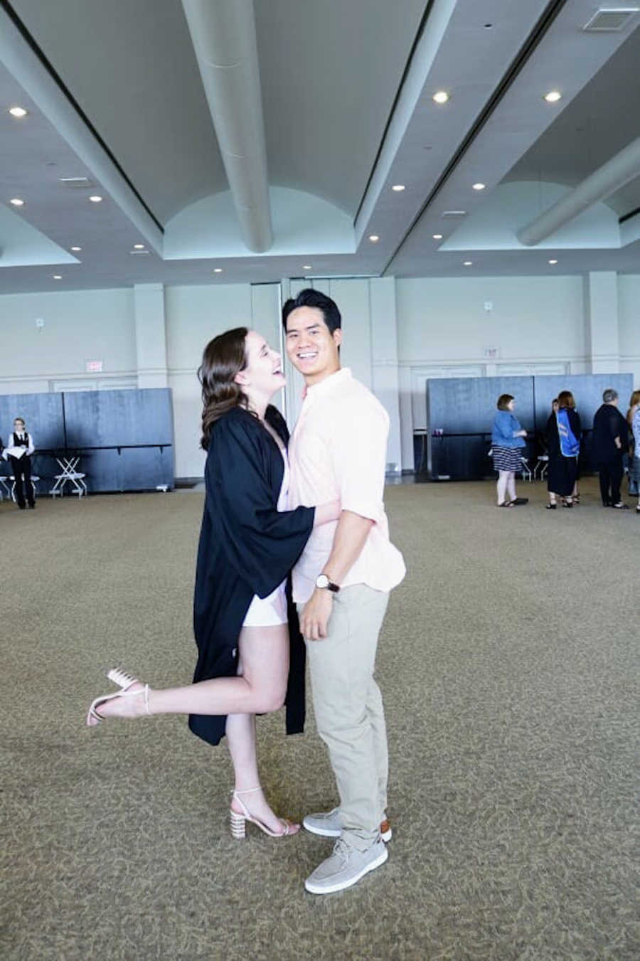 Woman in graduation robe holding boyfriend