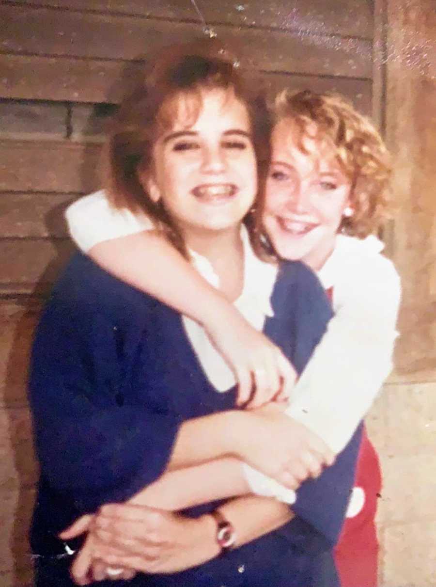 A young woman wraps her arms around a friend