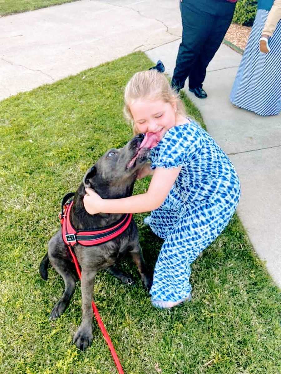 girl in blue dress smiles with pitbull