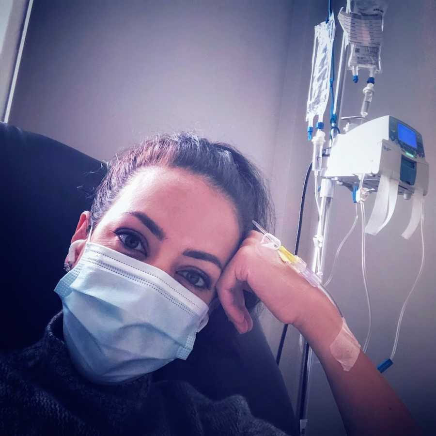 Woman wearing ponytail and facemask getting treatment by IV in hospital