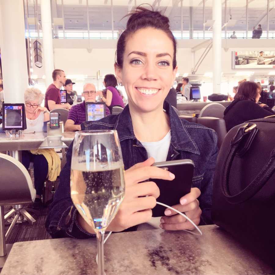 Woman smiling and holding phone in restaurant with glass of champagne