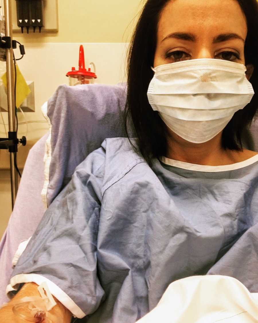 Woman wearing hospital gown and facemask lying in hospital bed