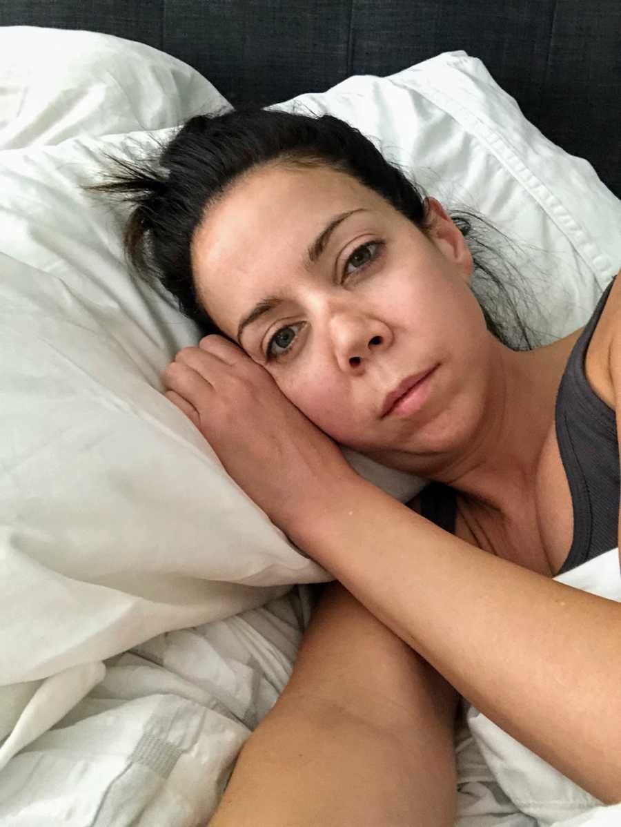 Woman lying in bed with white sheets