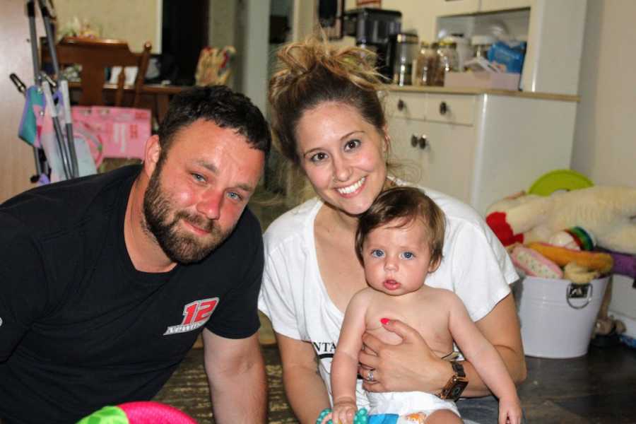 Mom and dad holding baby sitting on kitchen floor