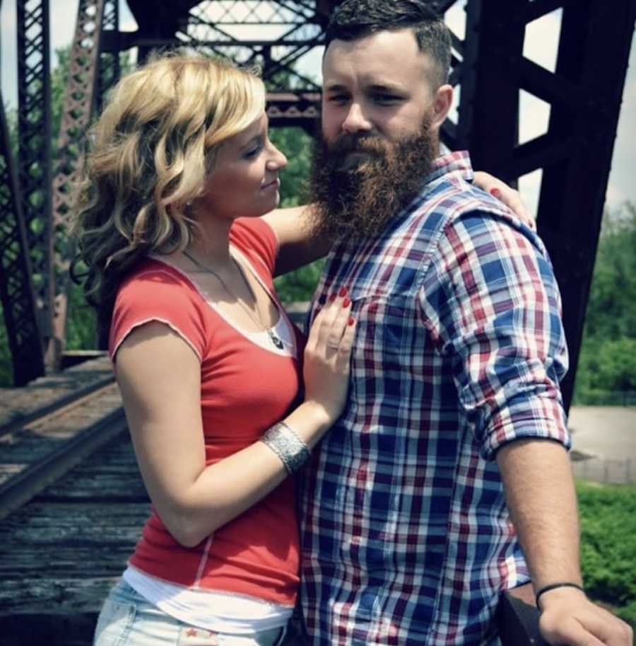 Couple posing standing on bridge outside