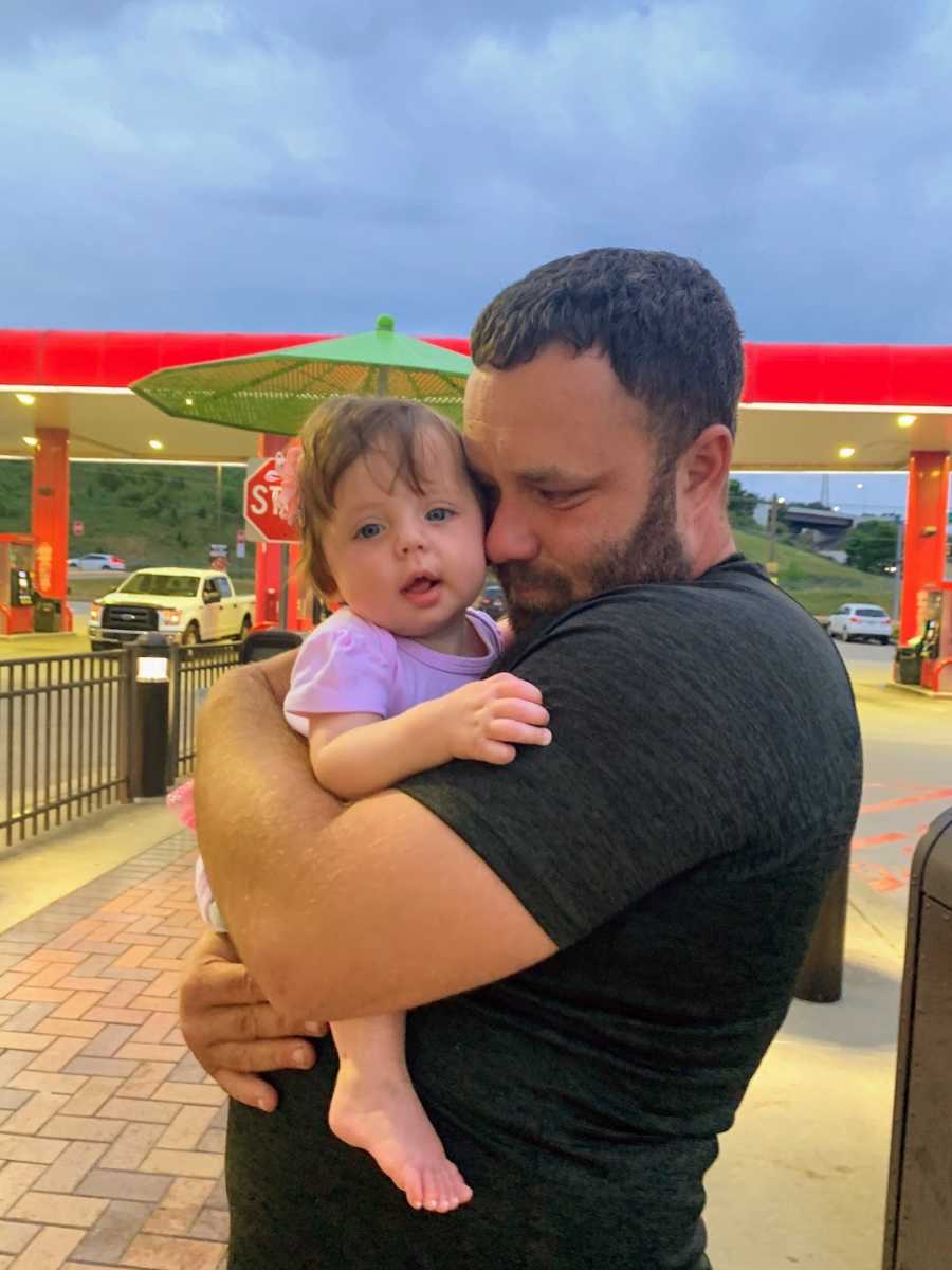 Father holding daughter while crying at a gas station