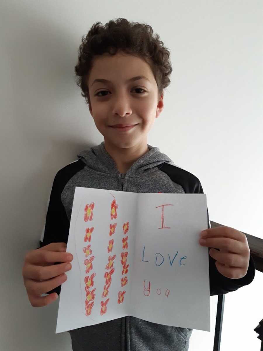 young boy holding sign "I love you"