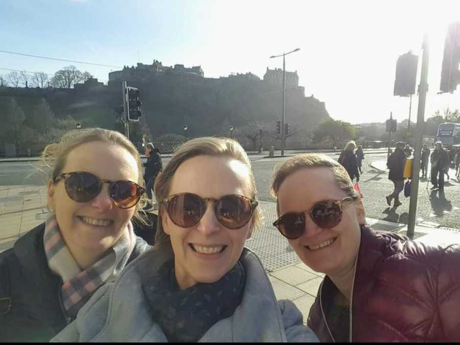 Three sisters wearing sunglasses taking smiling selfie