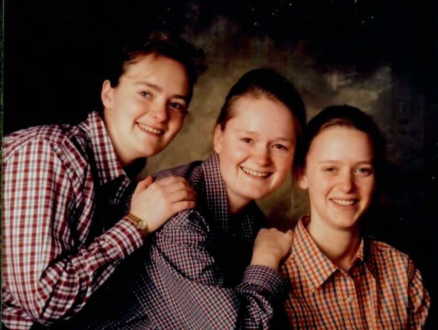 Three sisters with hands on shoulders posing