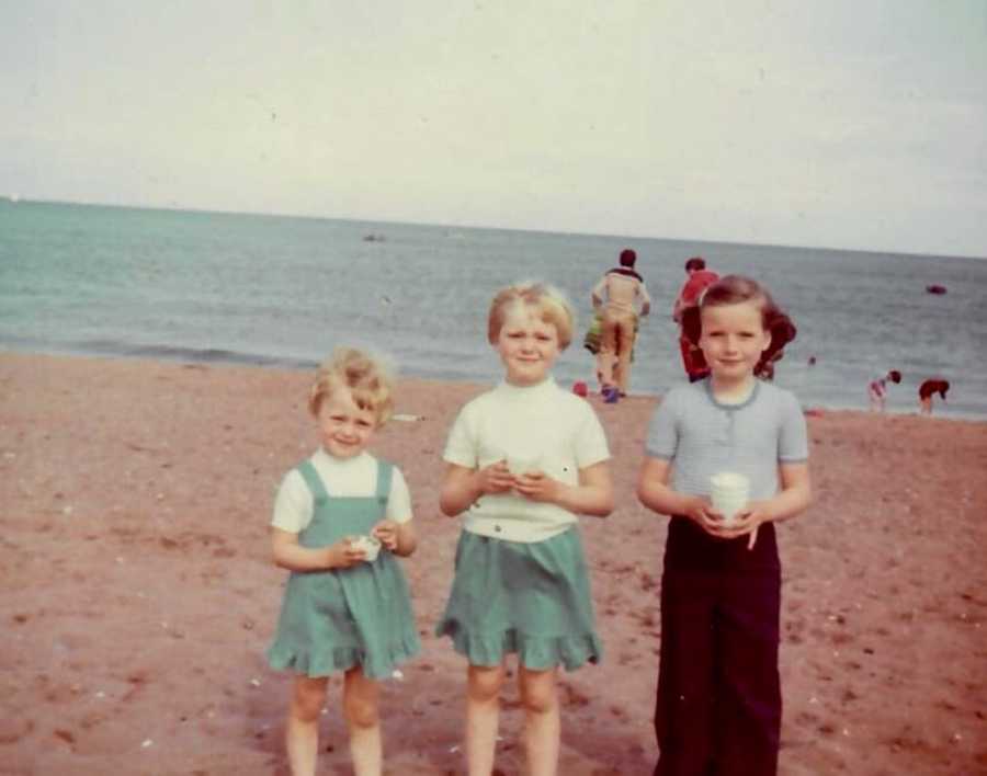 Three sisters standing on beach in front of ocean