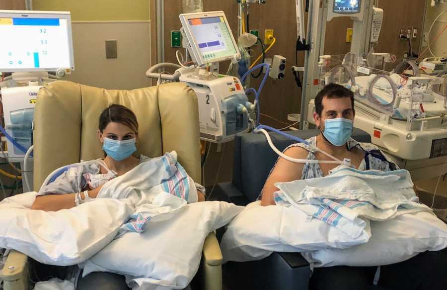 Husband and wife in hospital holding newborn boy twins wearing masks