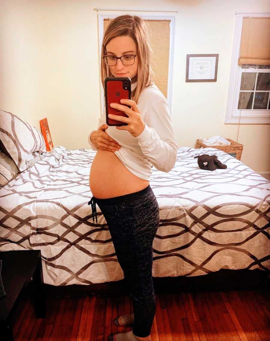 Pregnant woman taking belly picture in bedroom