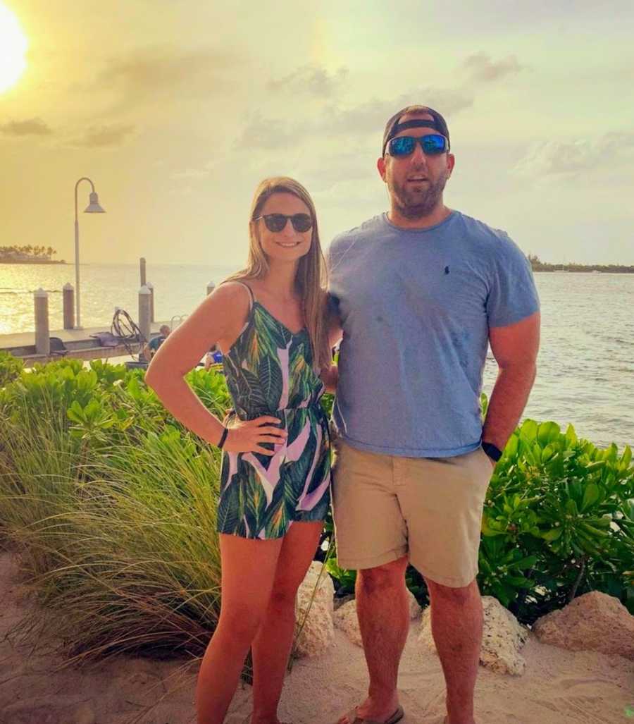 Husband and wife with arms around each other by lake