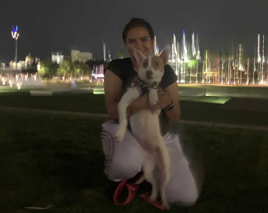 girl holding a dog in front of a city landscape