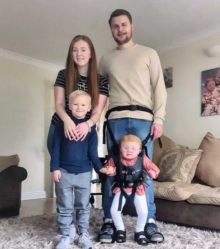 Family of four standing in living room smiling