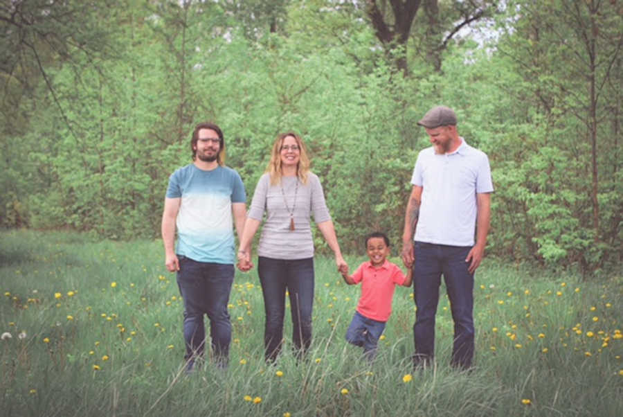 Family of four holding hands and standing outside