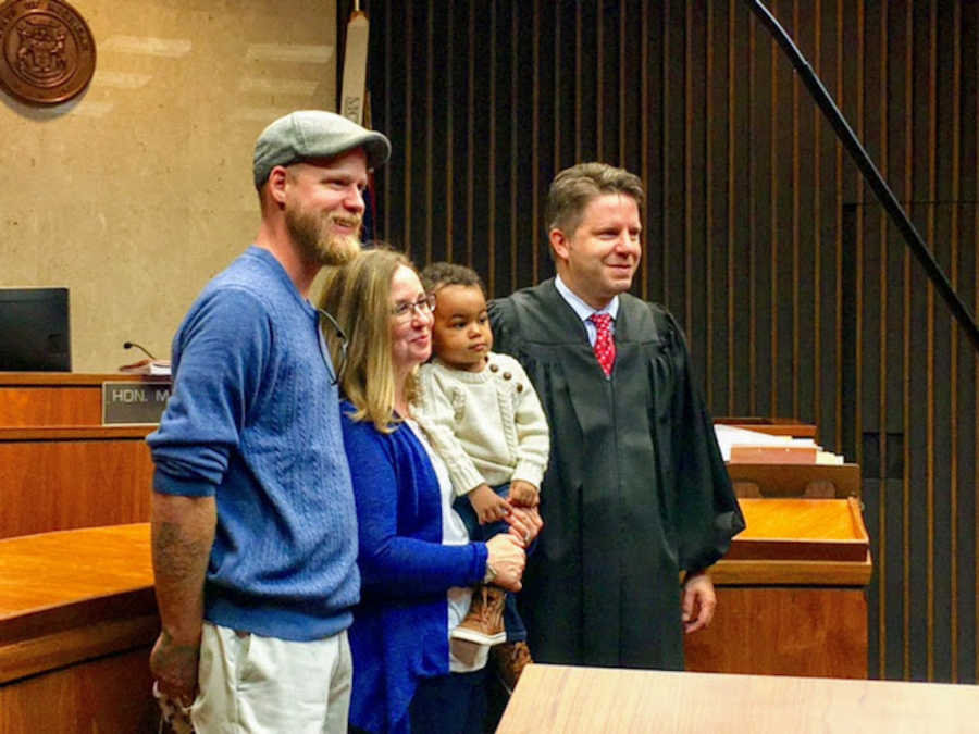 Family standing in adoption court with judge