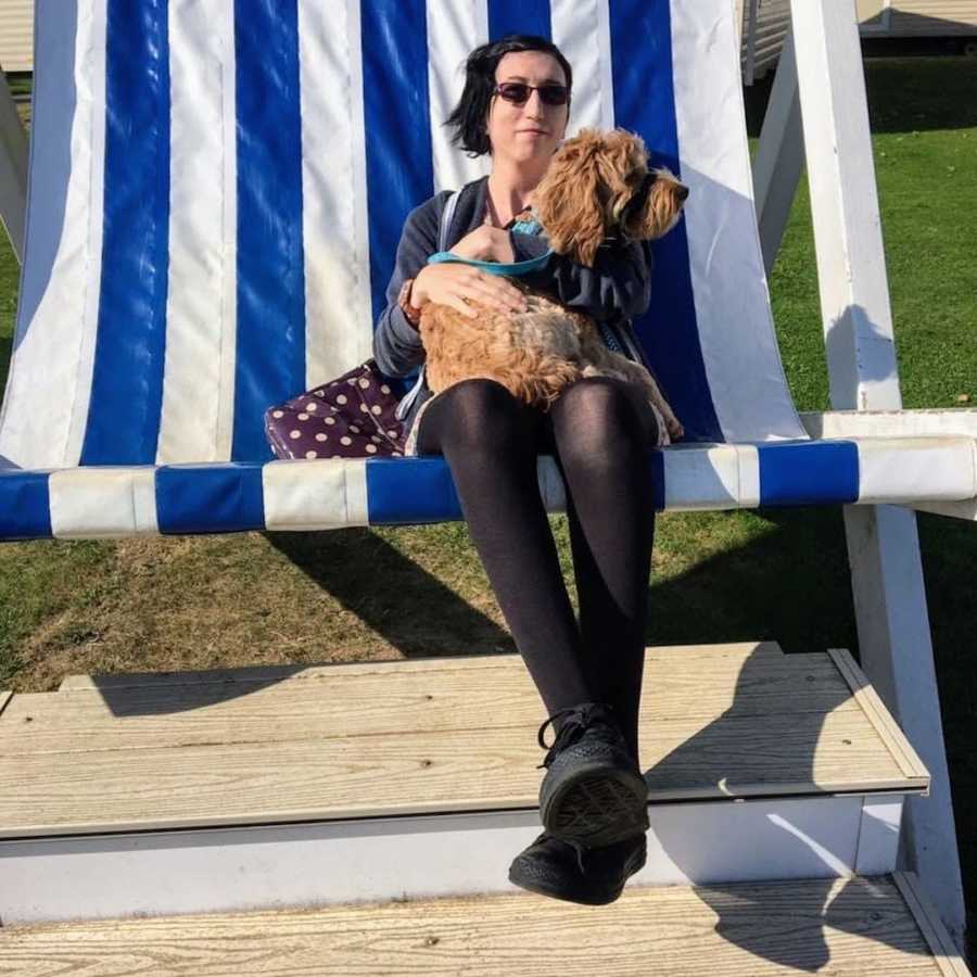 Woman with Goldendoodle sitting on blue and white striped chair