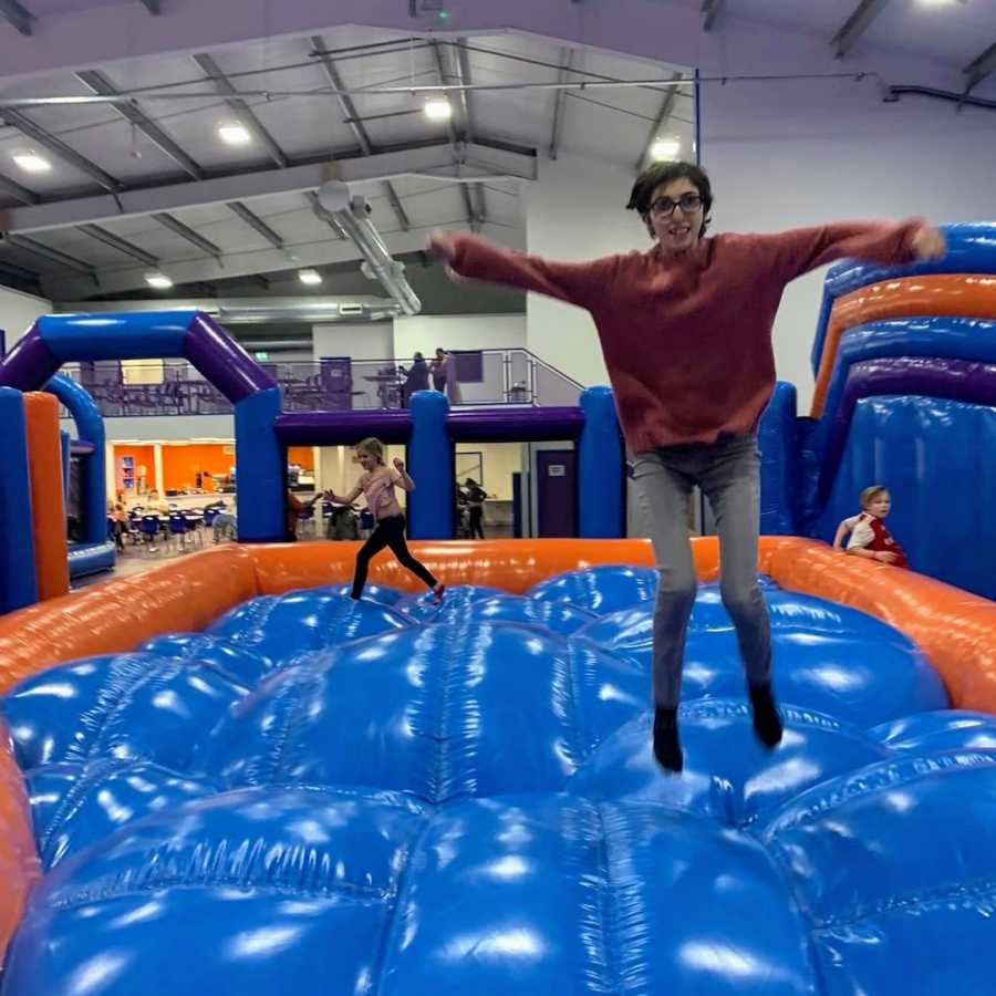 Woman jumping on blue and orange inflatable bouncy castle