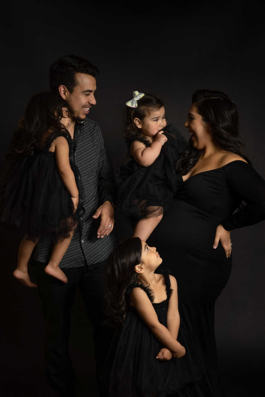 Family of 5 with pregnant mother wearing black and laughing
