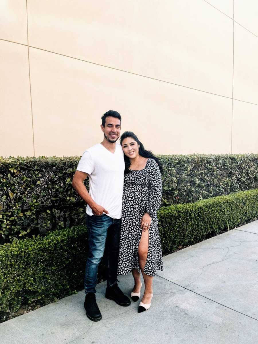 Young couple posing in front of green hedge