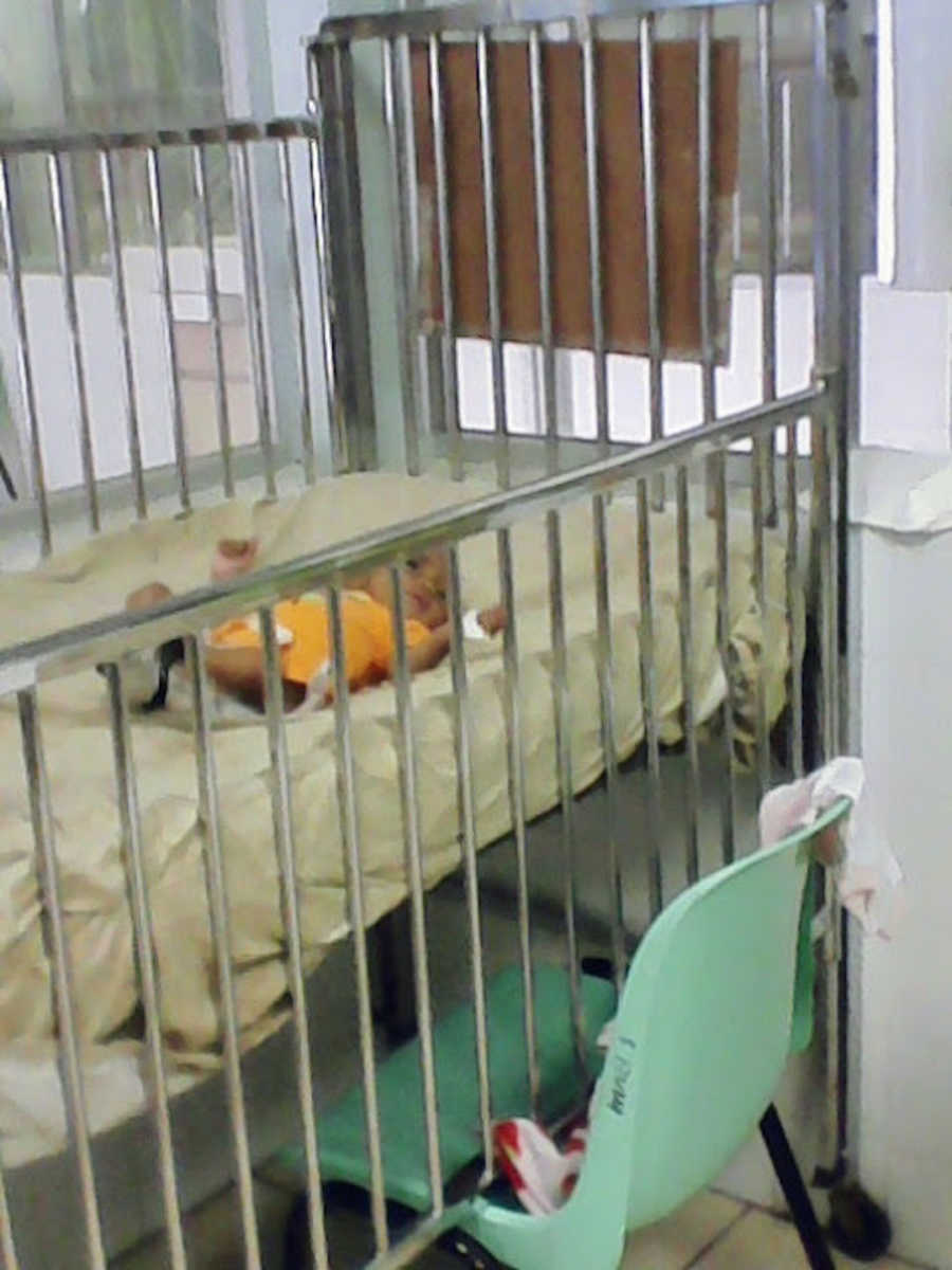 Baby wearing yellow in crib at hospital