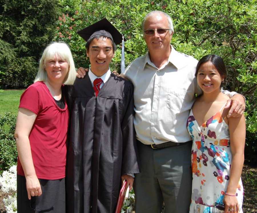 boy in graduation cap and gown with family