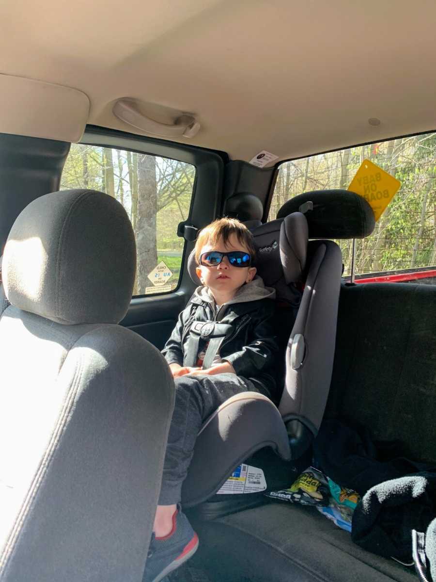 Autistic boy in car seat wearing sunglasses