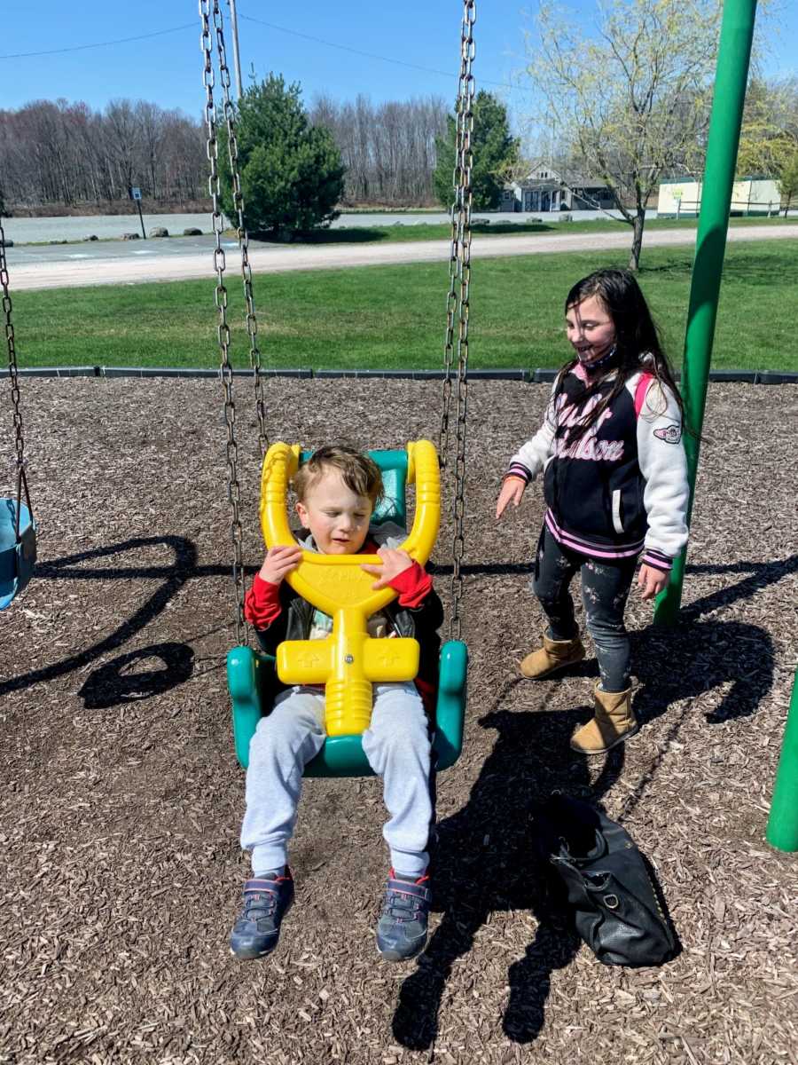 Sister pushes autistic brother on swing