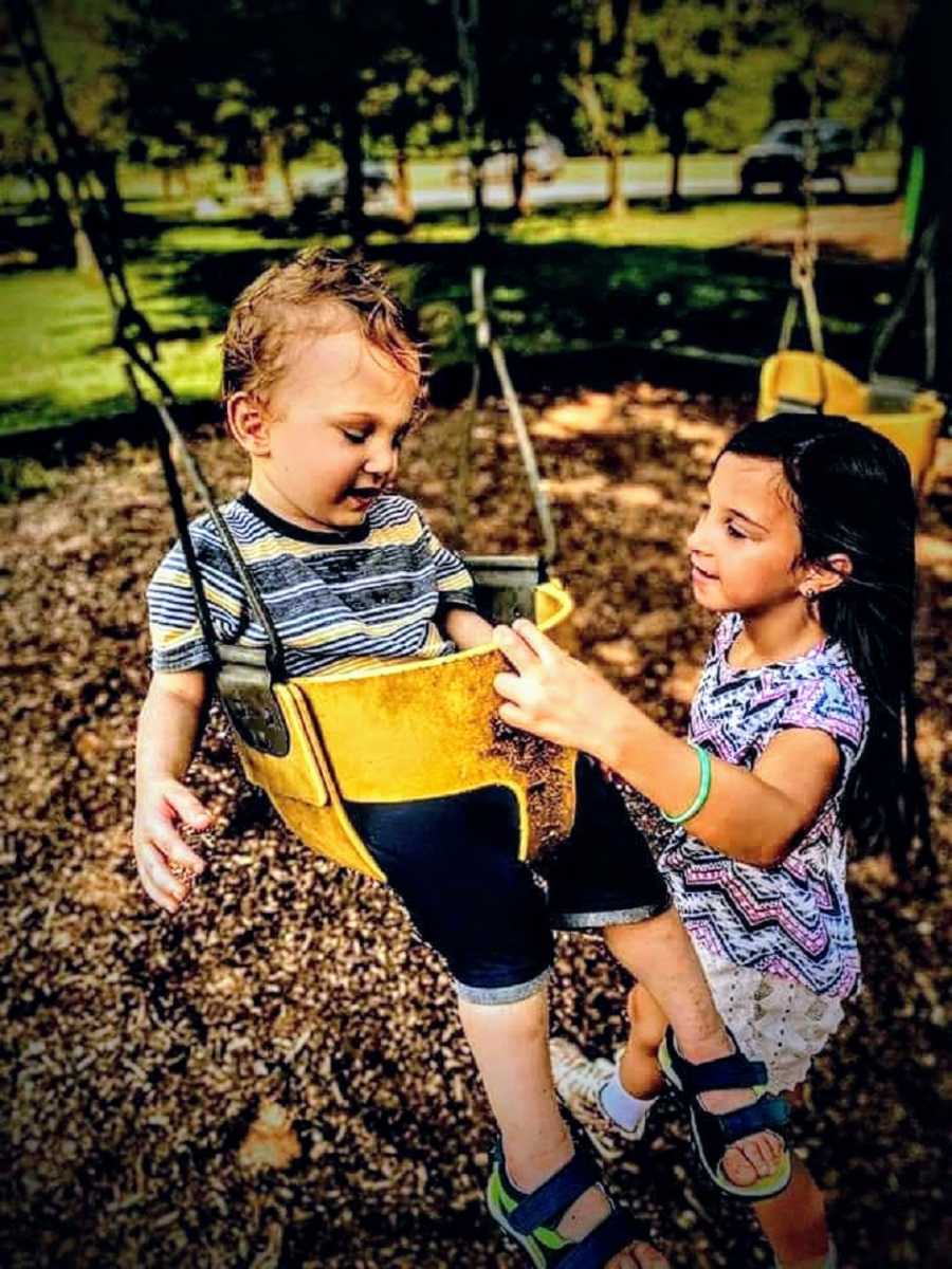 Girl plays with autistic brother on swing