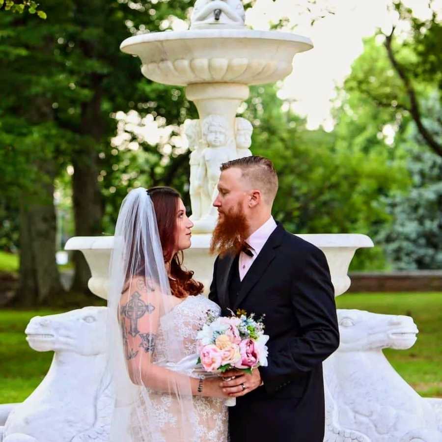 Bride and groom holding flowers near fountain