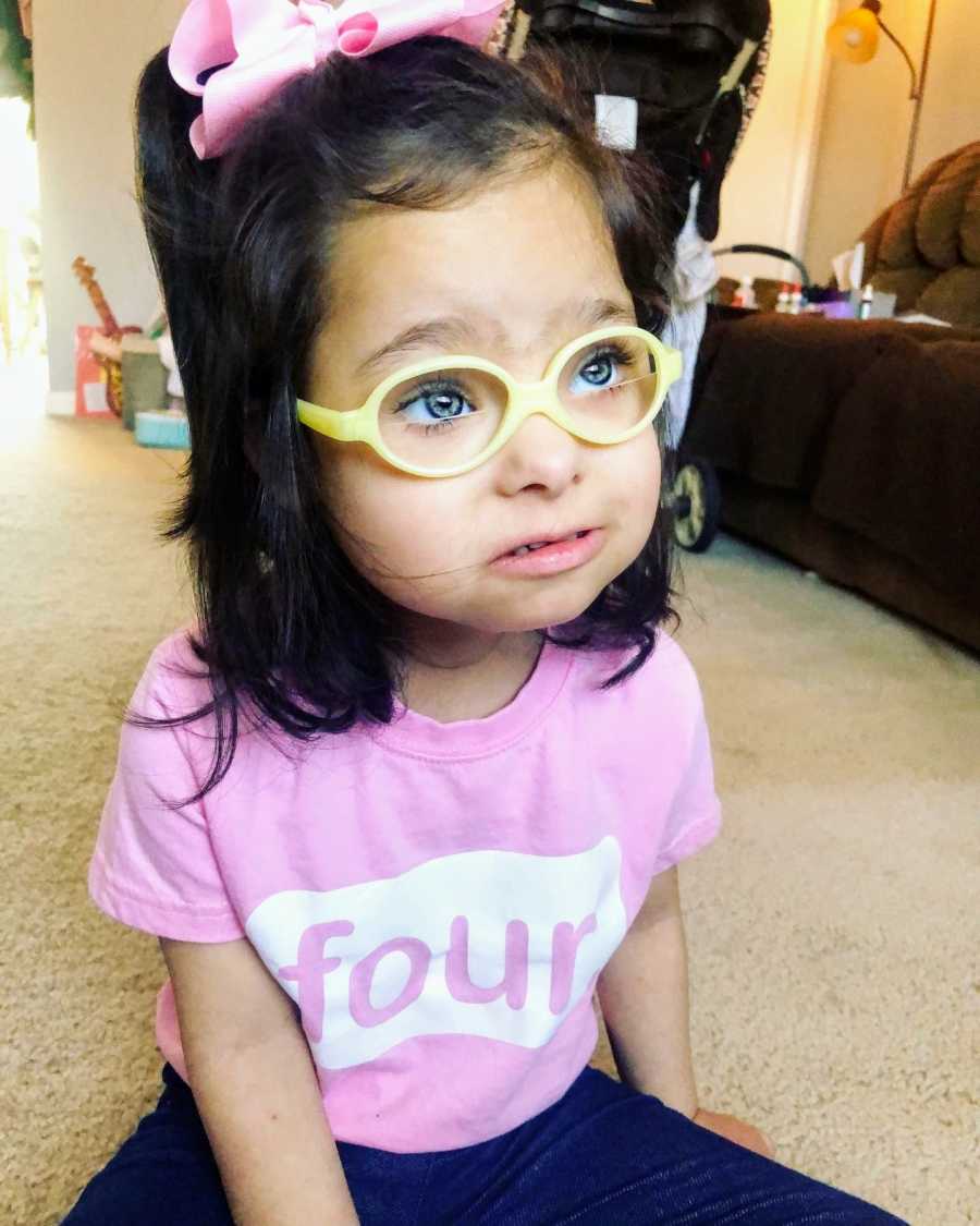 A girl with Down Syndrome wearing yellow glasses