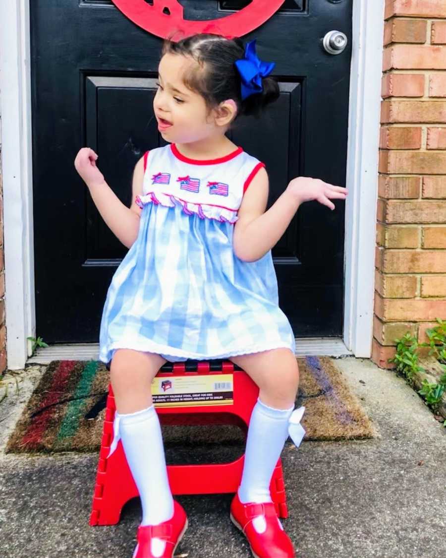 An adopted girl sitting on a stool wearing a dress