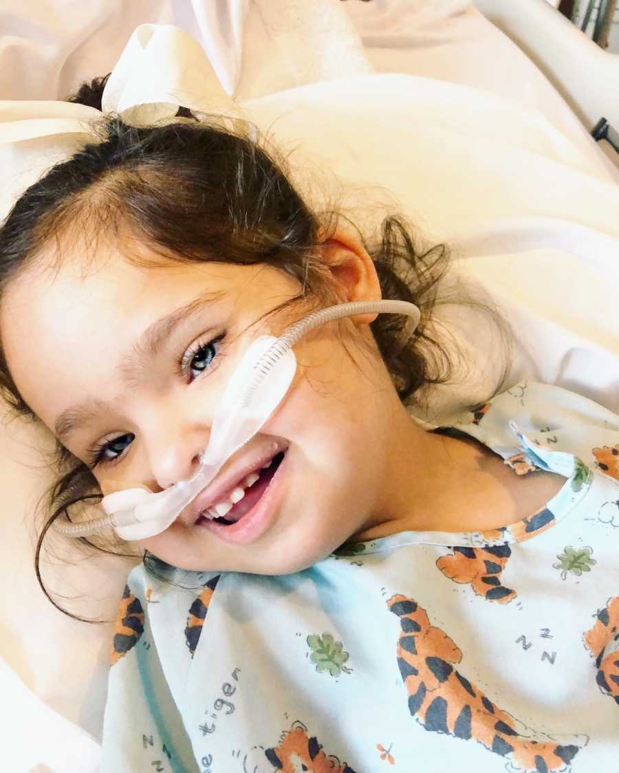 A girl with special needs smiles while wearing oxygen in the hospital