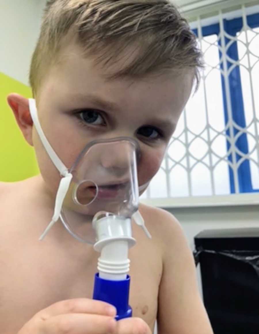 Young blonde boy wearing oxygen mask at hospital