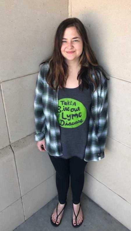 Girl leaning on wall posing for picture smiling