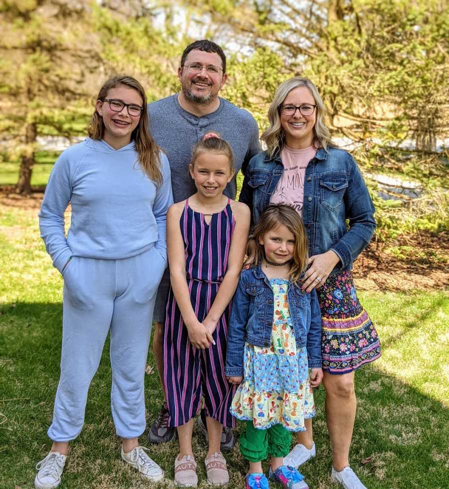 Foster family smiling outdoors in the grass