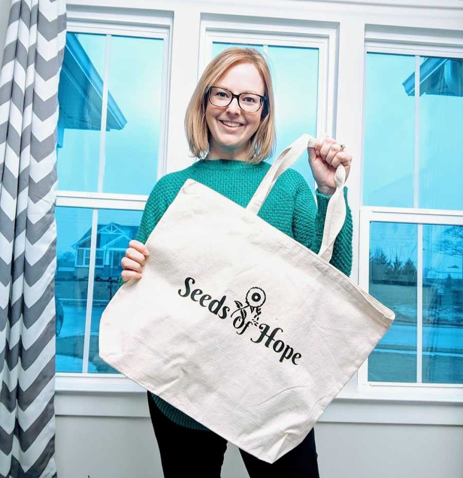 Woman holding nonprofit foster care tote bag, smiling