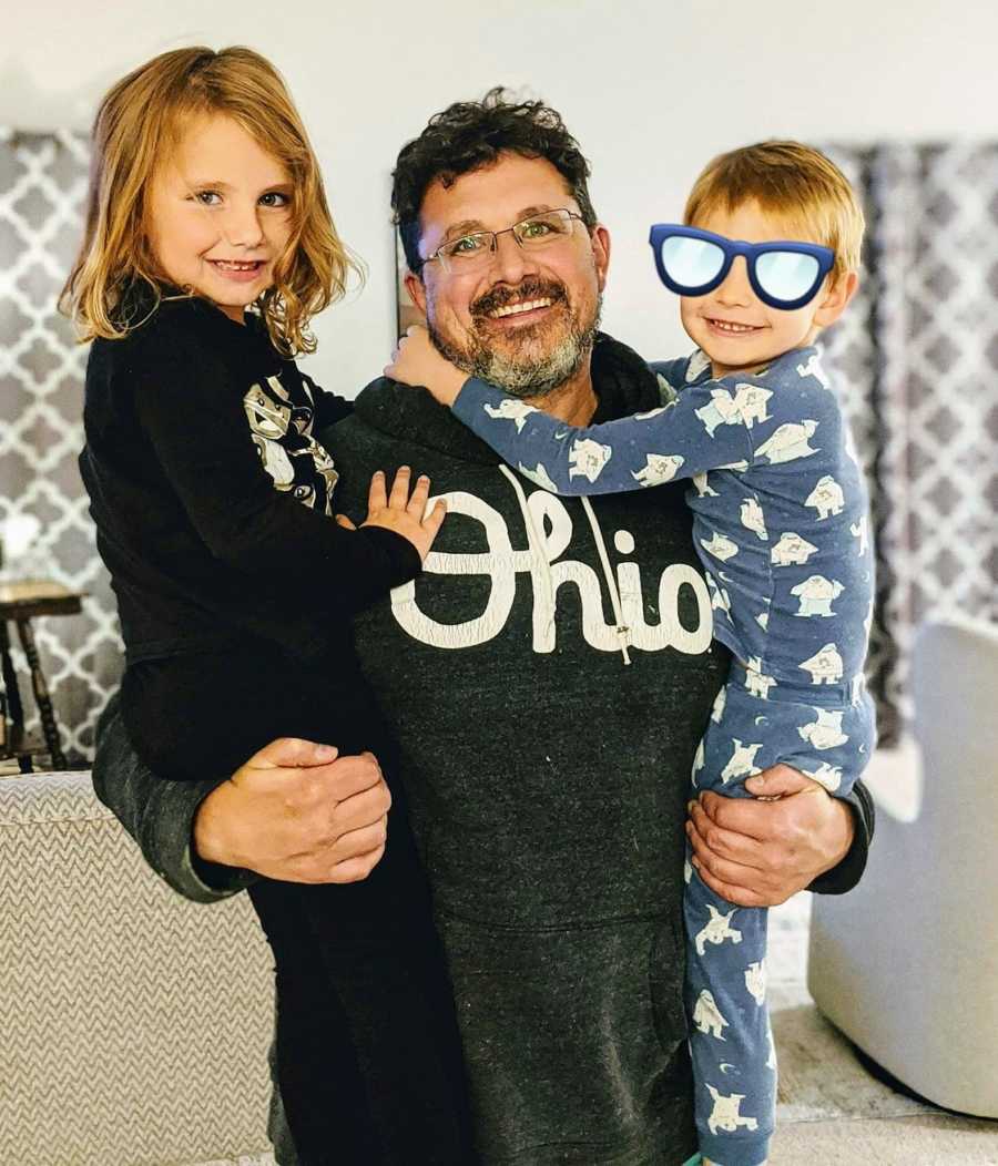 Foster dad holding daughter and foster son in pjs, smiling